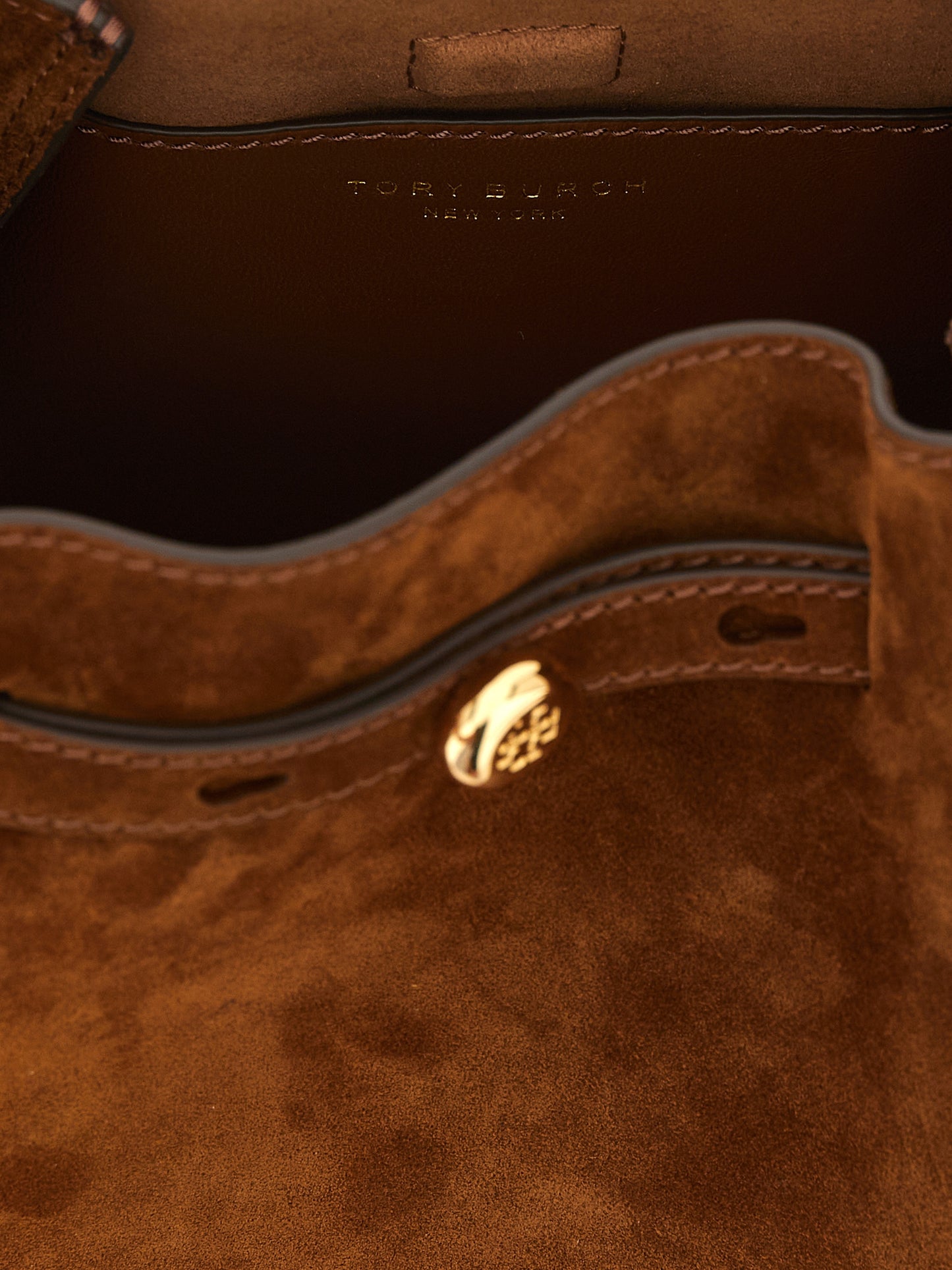 Crossbody Bucket Handbag by Tory Burch for women in bos taurus suede leather brown, gold & signature features an multi-faceted design with a secure , ample , and versatile crossbody-strap, shoulder-strap, handle & adjustable-strap for a multi-faceted finish.