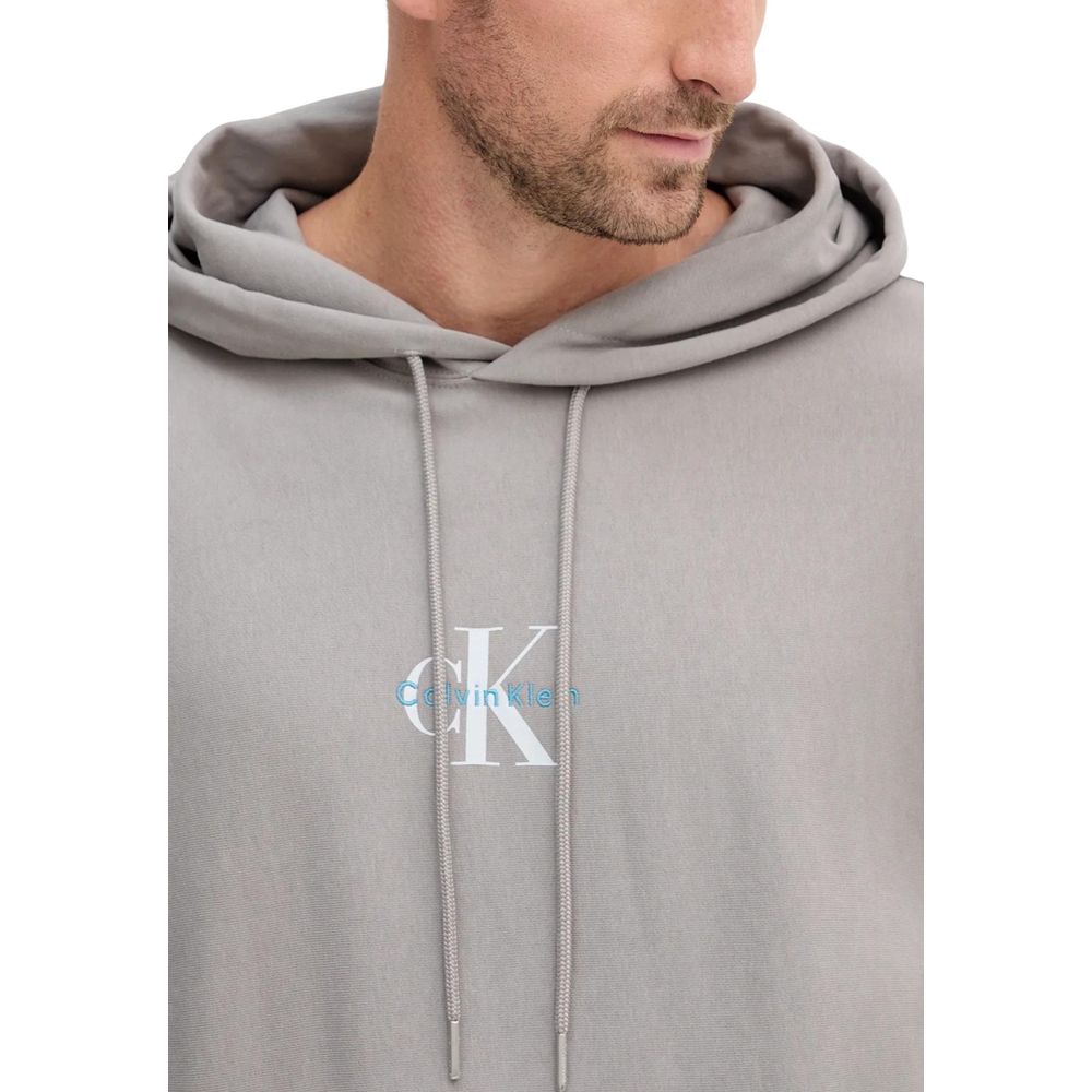 Hooded Hoodie by Calvin Klein Jeans for men in cotton terrycloth & polyester gray features a slouchy chic silhouette, detailed with a slouchy chic and a signature hooded neckline for an elevated aesthetic.