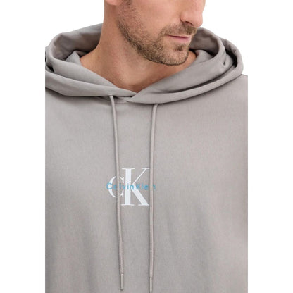 Hooded Hoodie by Calvin Klein Jeans for men in cotton terrycloth & polyester gray features a slouchy chic silhouette, detailed with a slouchy chic and a signature hooded neckline for an elevated aesthetic.