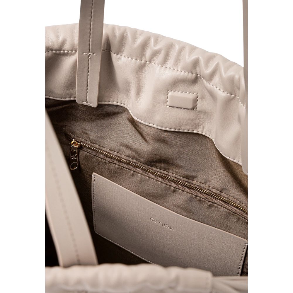 Large Tote Handbag by Calvin Klein for women in polyethylene & polyurethane beige features a ornamental silhouette, showcasing a secure drawstring, ample , and ornamental handle for a sophisticated look.