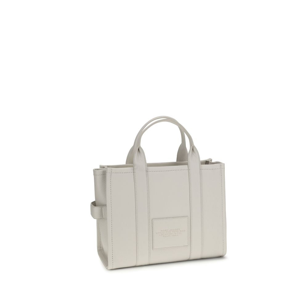 This Medium Tote Handbag by Marc Jacobs for women in bos taurus calf grained leather and white, patterned & monogram presents a sculptural silhouette featuring a secure zipper, ample , and versatile shoulder-strap, handle & adjustable-strap for a sculptural finish.