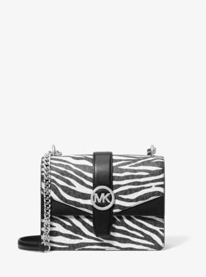 Small Crossbody Travel Tote Handbag by Michael Kors for women in synthetic polyurethane leather animal, black, silver, white & print features a versatile chic silhouette, meticulously detailed with a secure magnetic, ample built-in-compartments, and versatile crossbody-strap.