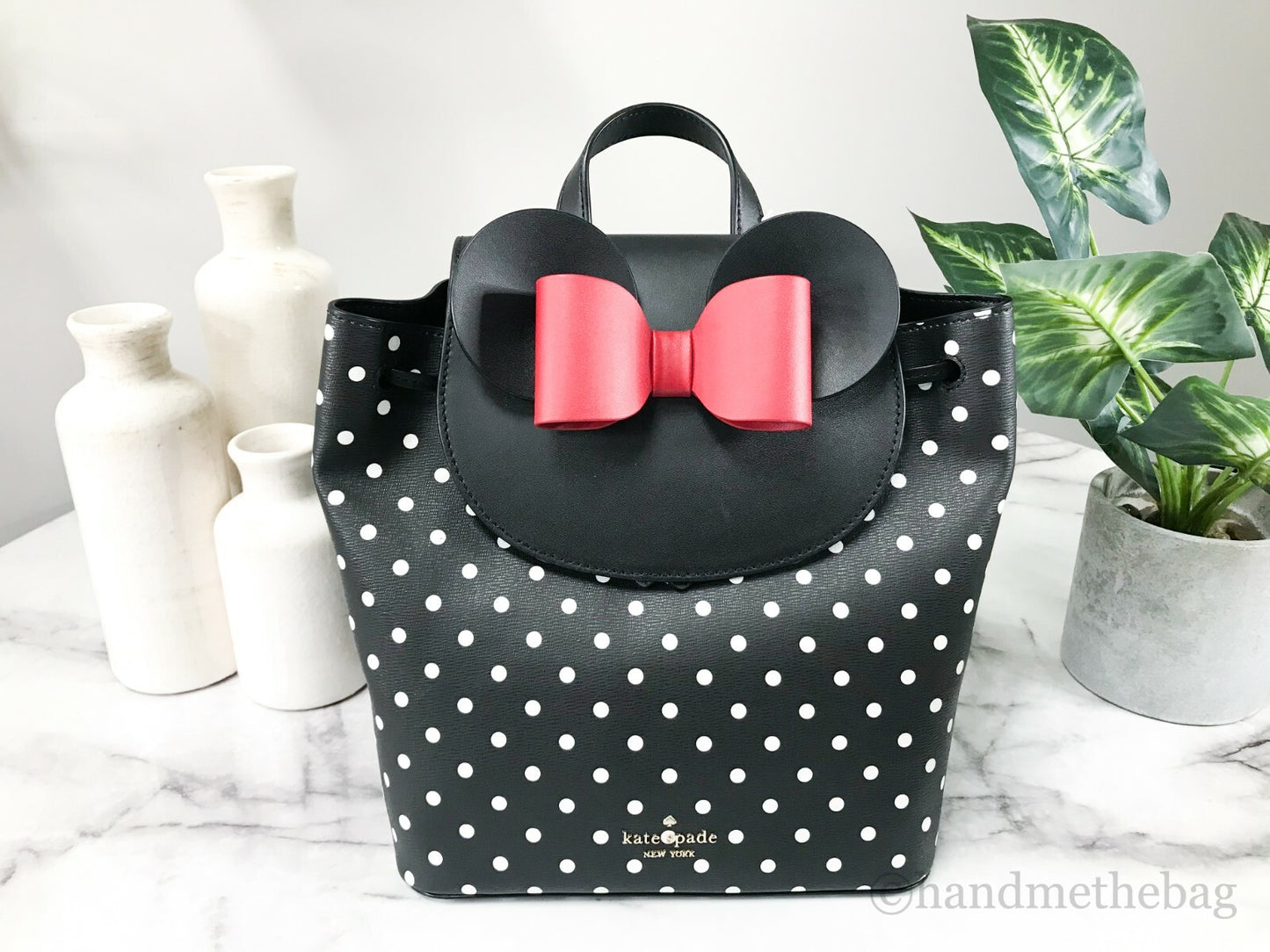 Medium Drawstring Backpack by Kate Spade for women in leather black, gold, silver & patterned features a stately Disney Minnie Mouse X Leather Medium Drawstring Backpack design, showcasing a secure snap, flap, drawstring & magnetic, ample , and versatile crossbody-strap & backpack-strap for a stately finish.