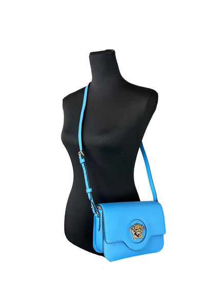 Small Crossbody Flap Handbag by Versace for women in leather blue & gold features an multi-faceted design with a secure flap & magnetic, ample , and versatile crossbody-strap, adjustable-strap & detachable-strap for a multi-faceted finish.
