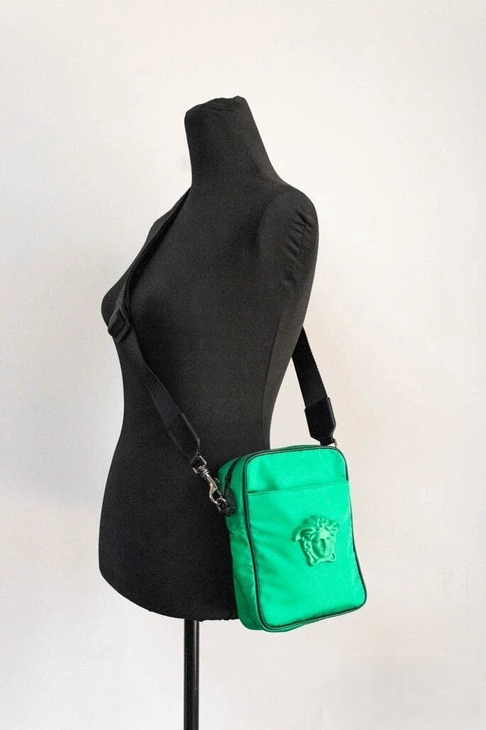 This Small Crossbody Travel Messenger Handbag by Versace for women in nylon fabric and black, green & patterned presents a sculptural silhouette featuring a secure zipper, ample cardholder, and versatile crossbody-strap, adjustable-strap & detachable-strap for a sculptural finish.