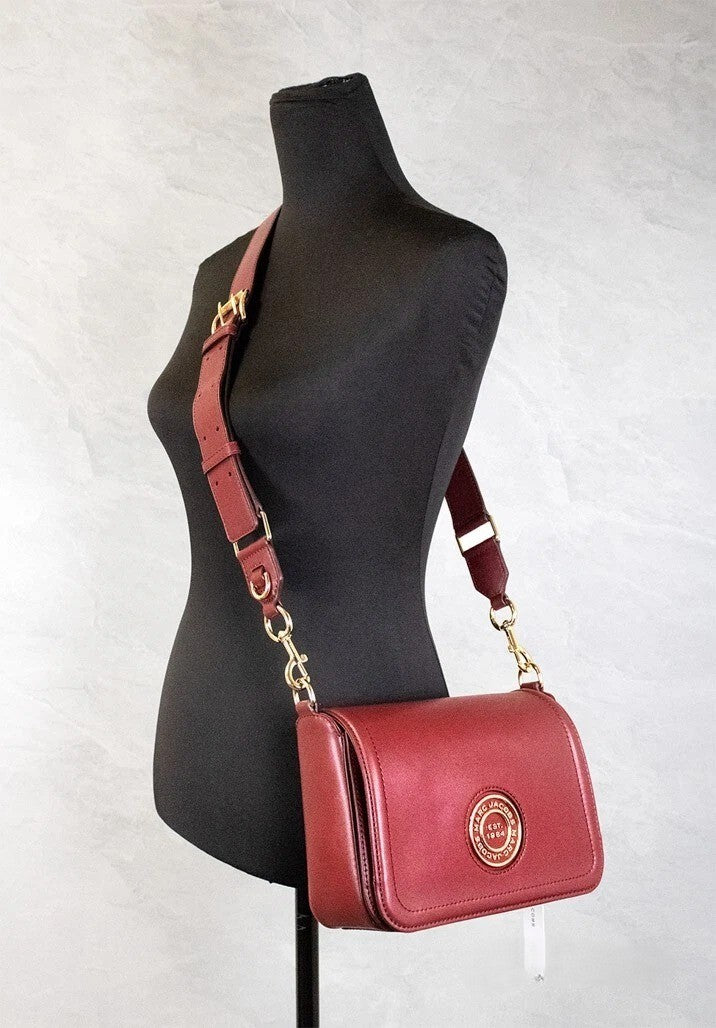 Medium Crossbody Flap Handbag by Marc Jacobs for women in leather & metal burgundy & gold features a multifaceted silhouette, showcasing a secure flap, zipper & magnetic and multifaceted with versatile crossbody-strap, adjustable-strap & detachable-strap for multifaceted style.