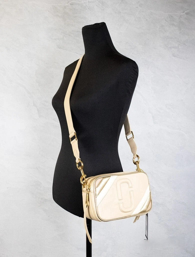 Travel Crossbody Camera Handbag by Marc Jacobs for women in leather beige, gold & ivory features a transformative sophistication silhouette, showcasing a secure zipper, ample built-in-compartments, and versatile crossbody-strap, adjustable-strap & detachable-strap for a transformative sophistication look.