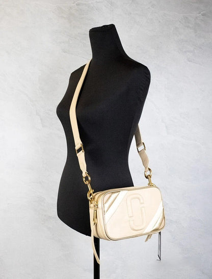 Travel Crossbody Camera Handbag by Marc Jacobs for women in leather beige, gold & ivory features a transformative sophistication silhouette, showcasing a secure zipper, ample built-in-compartments, and versatile crossbody-strap, adjustable-strap & detachable-strap for a transformative sophistication look.