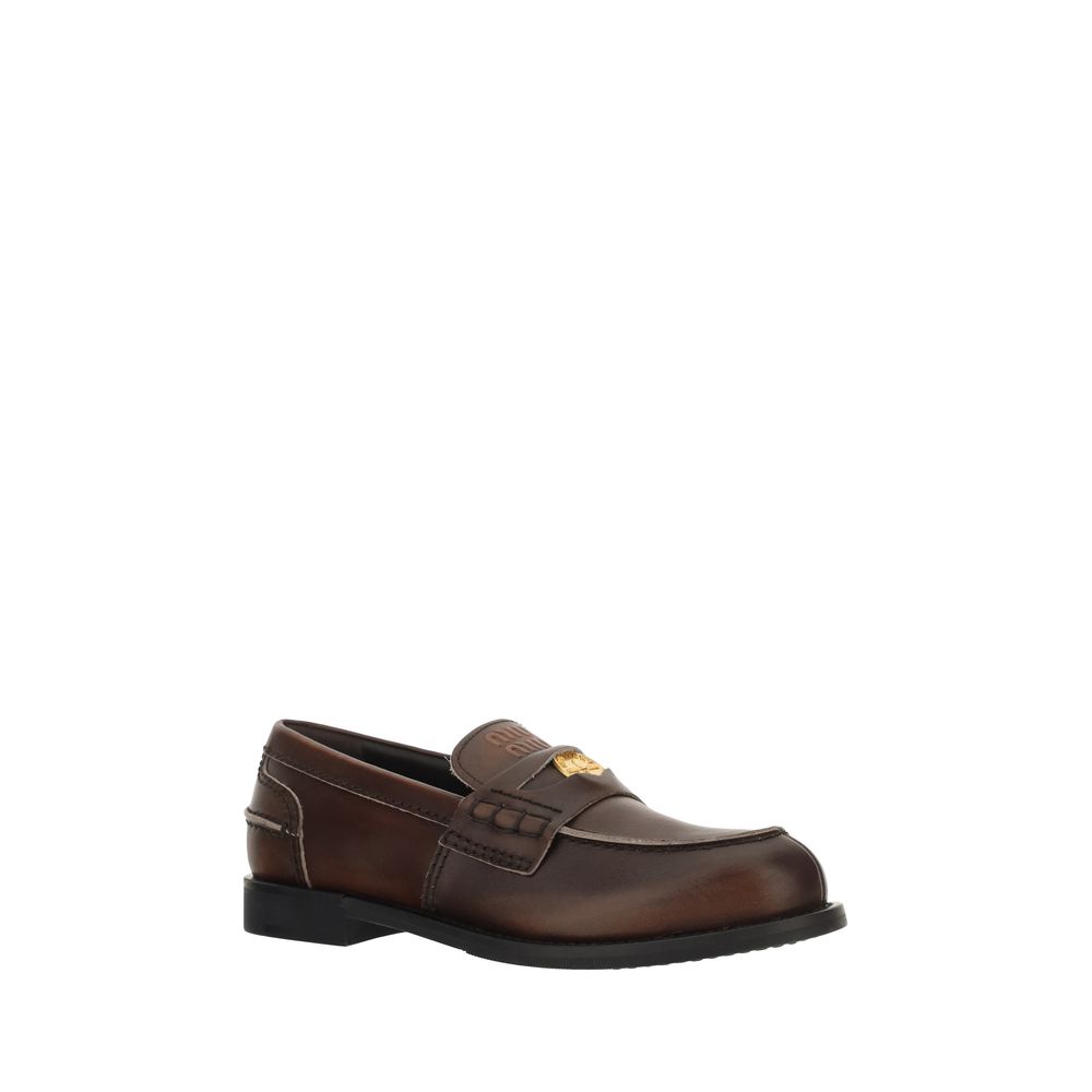 Loafer Slip-On Shoes by Miu Miu for women in bos taurus calf leather brown & signature features an effortless chic silhouette, showcasing the Women's Bos Taurus Calf Leather Loafer Slip-On Shoes design with an effortless chic block-heel and a for a effortless chic look.