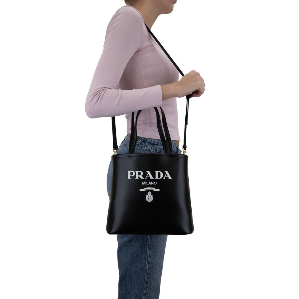 Tote Bag by Prada for women in calfskin leather black & print showcases a statuesque Calfskin Leather Tote Bag design, featuring a secure , ample , and versatile shoulder-strap, handle & detachable-strap for a statuesque finish.