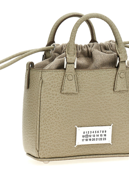 This Drawstring Tote Handbag by Maison Margiela for women in calfskin leather and gray presents a sculptural silhouette featuring a secure drawstring, ample , and versatile shoulder-strap & handle for a sculptural finish.