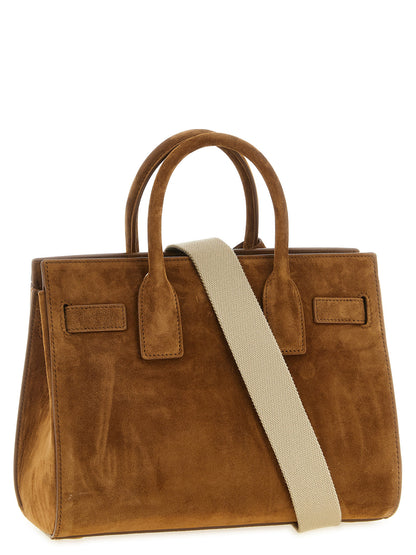 This Small East West Handbag by Saint Laurent for women in suede calfskin leather and brown & signature presents a sculptural silhouette featuring a secure , ample , and versatile adjustable-strap & handle for a sculptural finish.