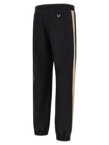 Joggers by Valentino Garavani for men in polyester black & gold features a polished silhouette with a polished athletic, reaching a polished long and finished with a polished .
