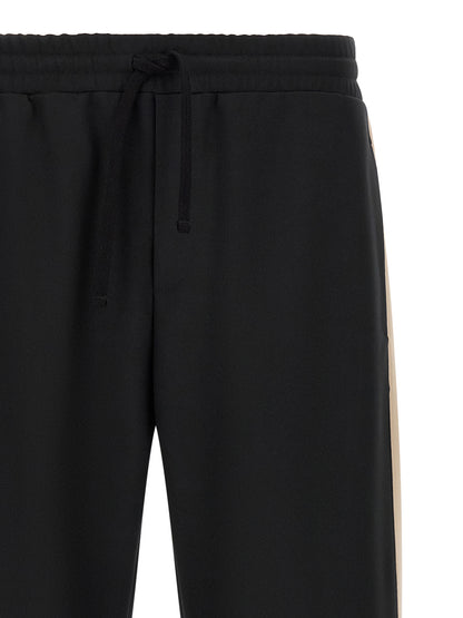 Joggers by Valentino Garavani for men in polyester black & gold presents a refined pantology silhouette, artfully defined by a refined pantology athletic, long, and a sophisticated .