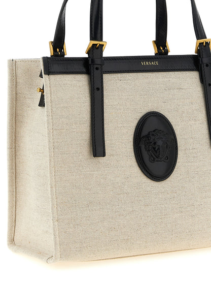 Medium Shopper Tote Bag by Versace for women in suede calfskin leather & cotton canvas beige & print features an utilitarian-chic silhouette, showcasing the Medusa Riviere Suede Calfskin Leather & Cotton Canvas Medium Shopper Tote Bag design with a secure , ample built-in-compartments, and versatile shoulder-strap, handle & adjustable-strap.
