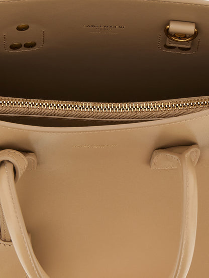 This Handbag by Saint Laurent for women in calfskin leather and beige presents a sculptural silhouette featuring a secure , ample , and versatile shoulder-strap, handle & adjustable-strap for a sculptural finish.