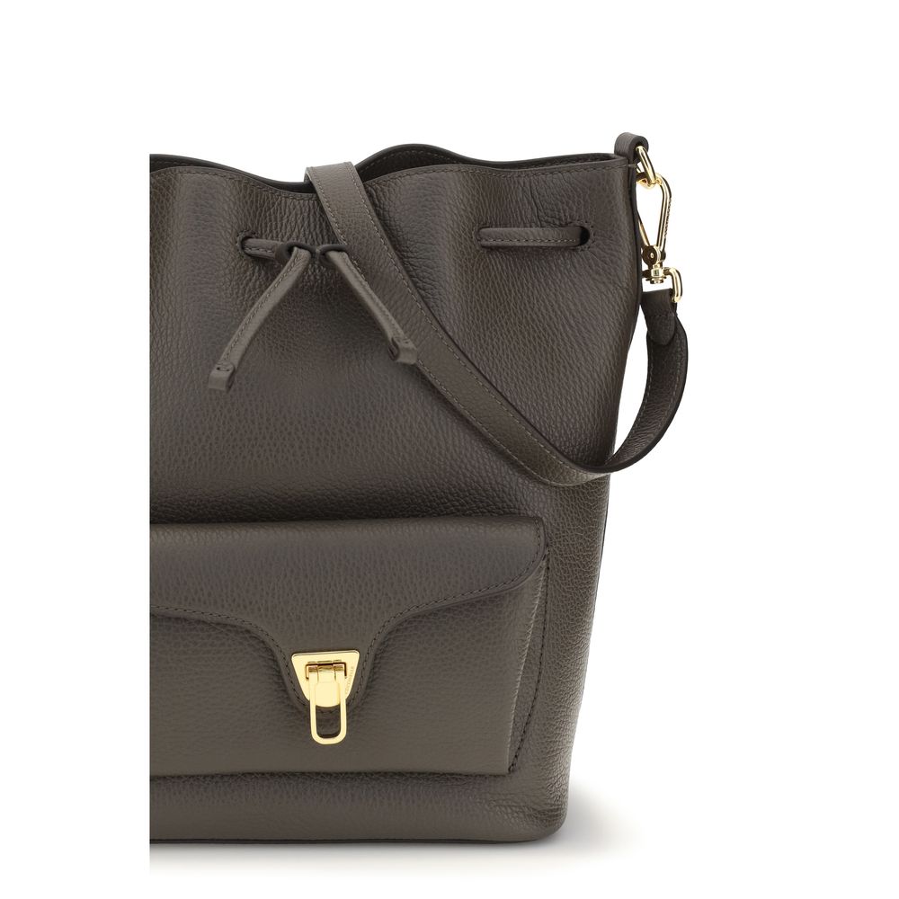 Bucket Handbag by Coccinelle for women in bos taurus calf grained leather brown, gold & signature features a effortlessly chic silhouette, showcasing a secure zipper & drawstring and ample external-pockets with versatile adjustable-strap & handle for a effortlessly chic finish.
