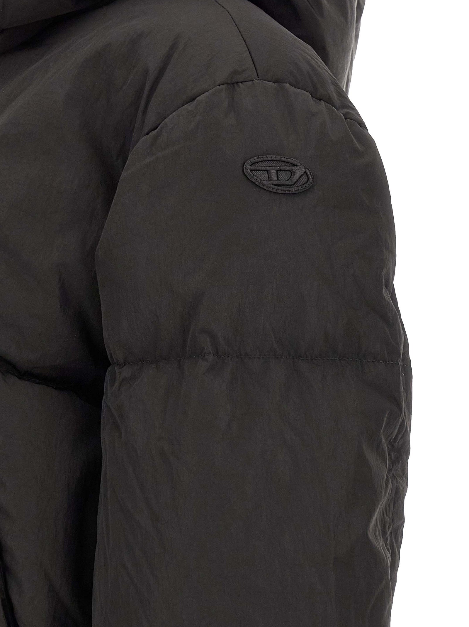 This Hooded Puffer Jacket by Diesel for women in polyamide black exhibits a edgy silhouette, meticulously detailed with functional pockets, hooded & insulated and a edgy for a edgy finish.