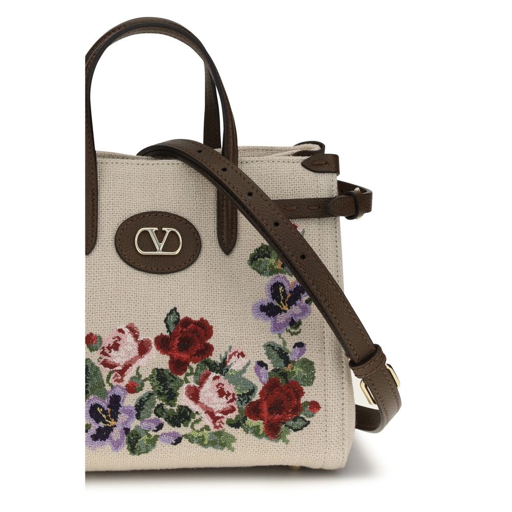 Small 2-in-1 Shoulder & Crossbody Bag by Valentino Garavani for women in grained leather & linen beige, natural, floral & signature features an effortlessly chic silhouette with a secure zipper & buckle, ample single-compartment, and versatile crossbody-strap, shoulder-strap, handle, adjustable-strap & detachable-strap for effortlessly chic everyday luxury.