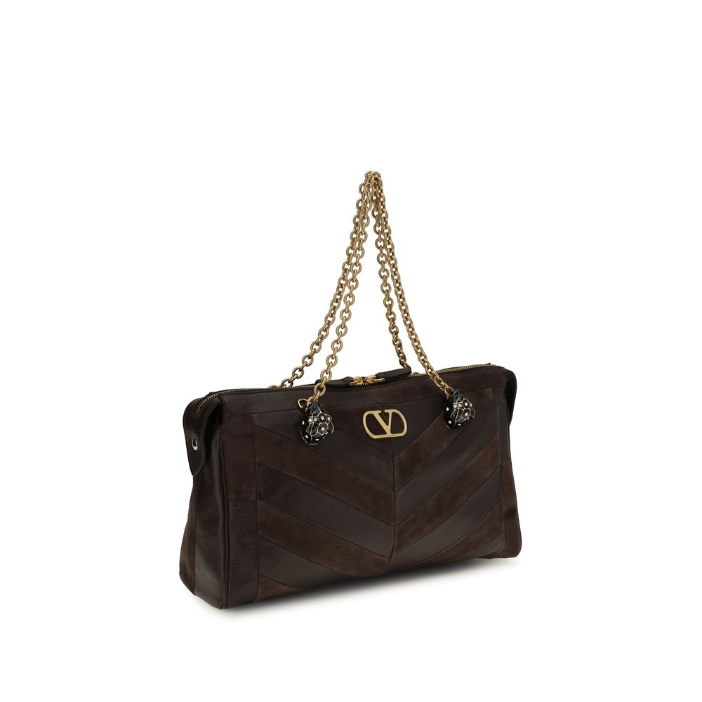 Medium Shoulder Bag by Valentino Garavani for women in bio-acetate & bos taurus calf leather brown, gold, chevron, signature & patchwork presents a versatile silhouette, showcasing a secure zipper and versatile single-compartment with versatile shoulder-strap, adjustable-strap & handle for a sophisticated look.