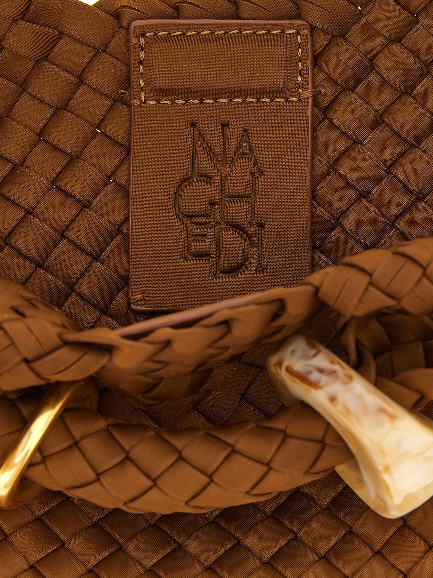 This Small Clutch Handbag by NAGHEDI for women in leather & neoprene and brown presents a sculptural silhouette featuring a secure , ample , and versatile shoulder-strap & handle for a sculptural finish.