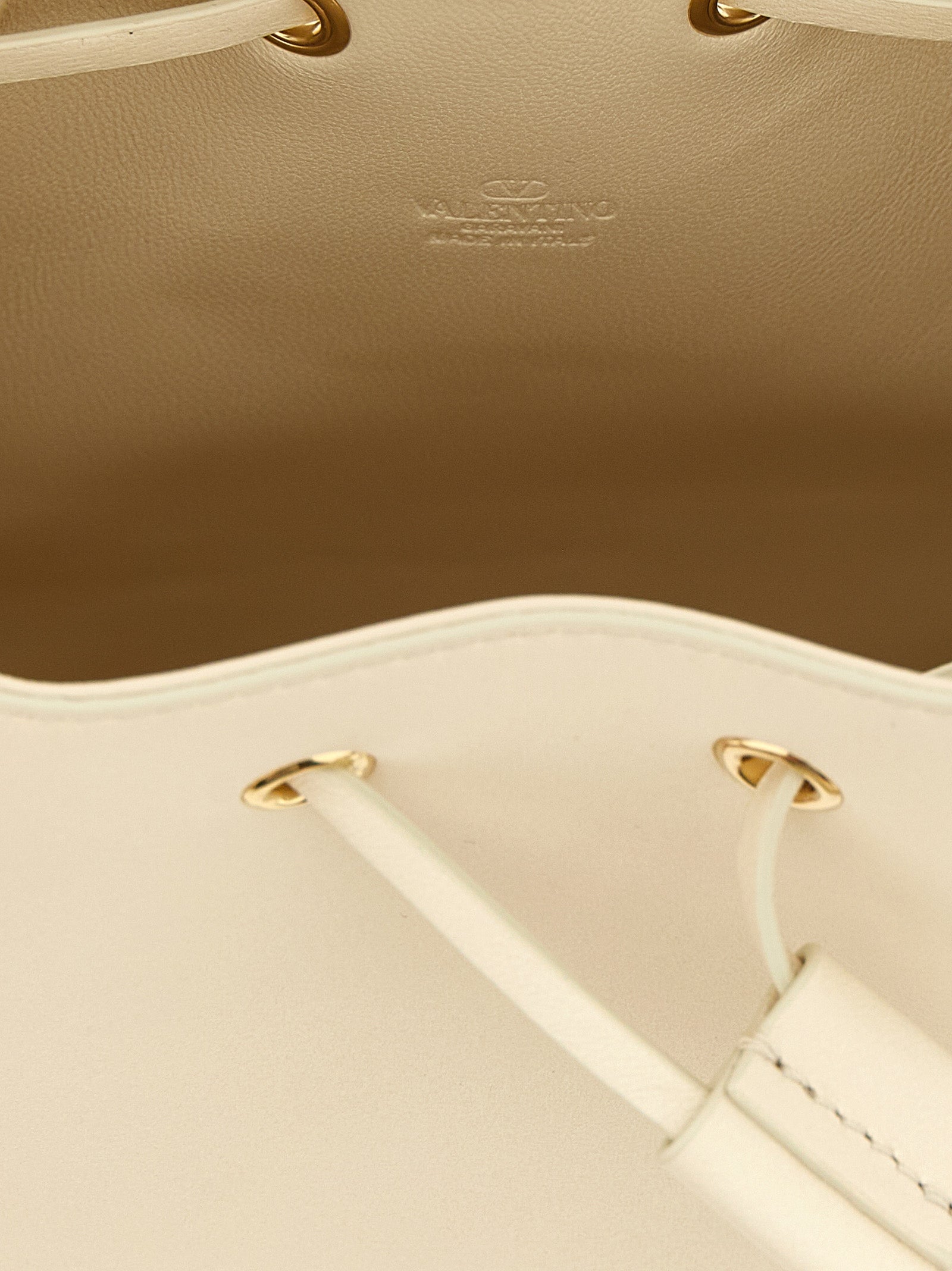 Medium Crossbody Bucket Handbag by Valentino Garavani for women in lamb leather gold, white & signature features a multifaceted silhouette, showcasing a secure drawstring & toggle and multifaceted with versatile crossbody-strap & shoulder-strap for multifaceted style.