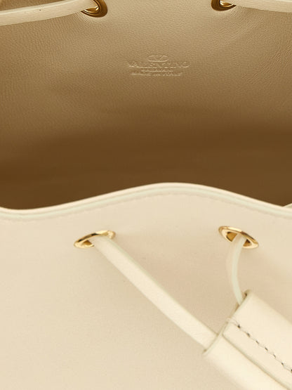 Medium Crossbody Bucket Handbag by Valentino Garavani for women in lamb leather gold, white & signature features a multifaceted silhouette, showcasing a secure drawstring & toggle and multifaceted with versatile crossbody-strap & shoulder-strap for multifaceted style.