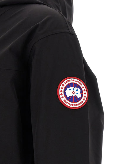 Hooded Rain Coat by Canada Goose for men in stretch polyamide black features an impenetrable silhouette, perfectly blending water-resistant, pockets, hooded & windproof with a sophisticated for a impenetrable finish.