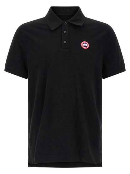 Polo Shirt by Canada Goose for women in cotton black presents a sleek silhouette, featuring a refined asymmetric neckline and short-sleeve for a sleek finish.