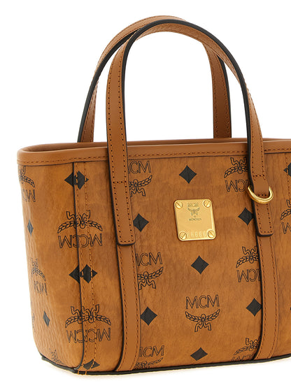 Mini Shopper Tote Bag by MCM for women in cotton canvas poly leather brown, gold, natural & monogram features an utilitarian-chic silhouette, showcasing the Visetos Cotton Canvas Poly Leather Mini Shopper Tote Bag design with a secure , ample , and versatile shoulder-strap & handle.