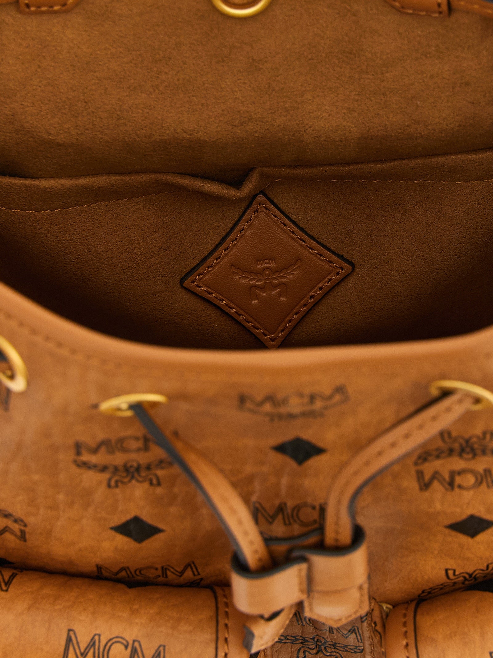 Medium Drawstring Backpack by MCM for women in polyester polyethylene polyurethane leather brown, gold & monogram features a utilitarian chic Aren Visetos Polyester Polyethylene Polyurethane Leather Medium Drawstring Backpack design with a secure flap & drawstring, ample , and versatile shoulder-strap, backpack-strap & adjustable-strap for a utilitarian chic finish.