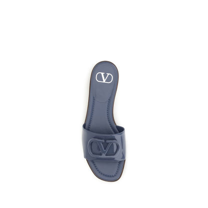 Flat Slider Sandals by Valentino Garavani for women in bos taurus calf patent leather blue features an exquisite silhouette, showcasing the exquisite V Logo Women's Bos Taurus Calf Patent Leather Flat Slider Sandals with a flat and open toe style.