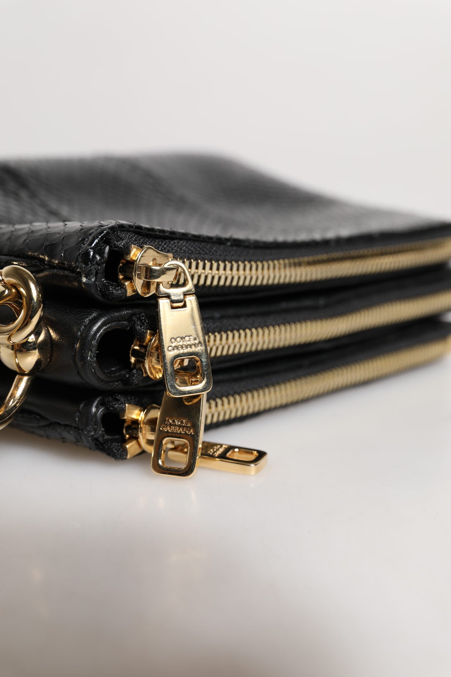 Shoulder Sling Clutch Bag by Dolce & Gabbana for women in exotic leather black & gold features a statuesque silhouette, showcasing a secure zipper and statuesque with versatile shoulder-strap, adjustable-strap & detachable-strap for a statuesque finish.